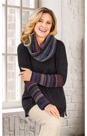 Dunkelgrauer Pullover mit rundem Ausschnitt, weite Passform, mit buntem gestricktem Schlauchschal und langen gestrickten Armstulpen in Blau-, Rot- und Grautönen, getragen von sitzender Frau mit verschränkten Armen