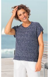 Locker sitzendes Strickshirt in dunkelblau mit weißem Fadenmuster, kurzärmlig, Rundhalsausschnitt, gerade geschnitten, getragen von stehender Frau am Meer