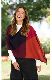 Dreifarbiger Poncho in Dunkelrot, Rostrot und Schwarz, asymmetrisches Design, offene Form ohne Verschluss, getragen von lächelnder Frau im Freien
