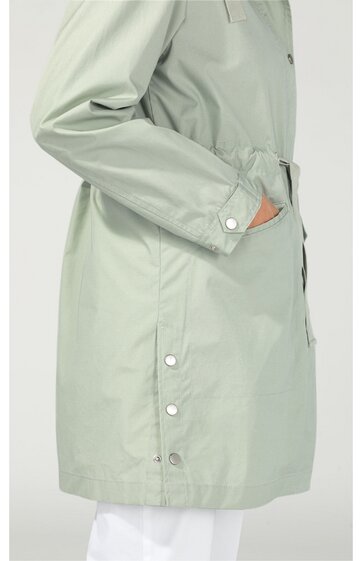 Hellgrüner Parka mit Knöpfen an der Fronttasche und am Ärmel, gerade geschnitten, Taillenzug, lange Ärmel, seitliche Taschen, getragen von seitlich stehendem Modell