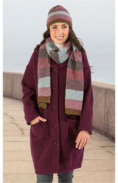 Damenmantel bordeauxrot, gerade geschnitten, mit Knöpfen, aufgesetzten Taschen, getragen von stehendem weiblichen Modell, dazu Schal und Mütze in Streifenmuster in Grau, Bordeaux und Ocker
