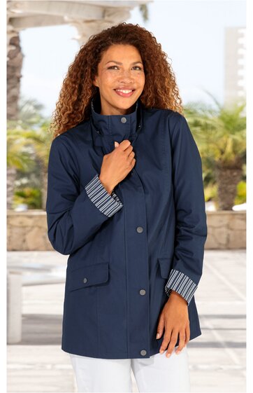 Dunkelblaue lange Jacke mit Stehkragen, verdeckter Knopfleiste, langen Ärmeln mit gestreiftem Umschlag, zwei aufgesetzten Taschen mit Klappen, getragen von stehender Frau