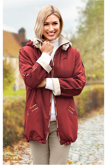 Damenjacke in rostrot mit weißen und grauen Ziernähten, Stehkragen, Reißverschluss, lange Ärmel mit weißen Bündchen, Gesäßlänge, getragen von lachender stehender Frau mit beigen Hosen