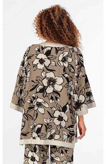 Beiger Pullover mit großem weißen und schwarzen Blumenmuster, lockere Passform, 3/4-Ärmel mit beigem Umschlag, am Rücken getragen von stehender Person