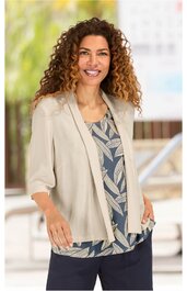 Leichte beige Blazerjacke mit kurzen Ärmeln, offener Front, getragen von lächelnder Frau mit lockigen braunen Haaren, darunter blau-grünes Top mit blattförmigem Muster, getragen zu dunkelblauer Hose