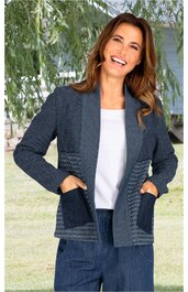 Dunkelblaue Strickjacke mit hellblauen geometrischen Mustern an Taschen und unteren Ärmelteilen, offenes Vorderteil, lange Ärmel, getragen von lächelnder Frau mit weißen T-Shirt und dunklen Hosen, entspannte Pose mit Händen in Taschen