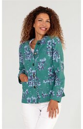 Grüne Bluse mit lila und weißen Blumenmuster, Knopfleiste vorne, lange Ärmel, taillierte Form, getragen von stehender Frau mit lockigem Haar, seitlich schräg zur Kamera gewandt