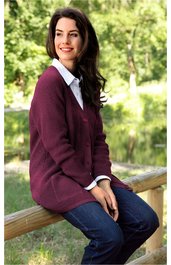 Dunkelroter Cardigan mit V-Ausschnitt, lange Ärmel, offen getragen über weißem Hemd, getragen von sitzender Frau, klassische Passform, kombiniert mit blauen Jeans
