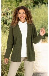 Olivegrüne Strickjacke ohne Verschluss, mit aufgesetzten Taschen, lange Ärmel, offener Schnitt, getragen von lächelnder Frau in weißem Rollkragenpullover und hellbeigen Hosen, stehende Pose