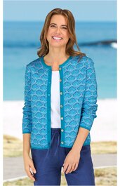 Tropfenblaues Strickjacke mit rundem Ausschnitt, goldfarbene Knöpfe, langärmlig, mit geometrischem Muster, getragen von lächelnder Frau stehend vor Strandhintergrund