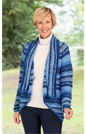 Strickjacke in verschiedenen Blautönen mit Streifenmuster, offene Front, lange Ärmel, gerade geschnitten, getragen von lächelnder stehender Frau mit kurzem blonden Haar, kombiniert mit cremefarbenem Rollkragenpullover und schwarzer Hose