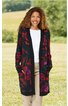 Lange Strickjacke in Dunkelblau mit buntem Blumenmuster, offene Vorderseite, lange Ärmel, zwei Eingrifftaschen, getragen von stehender Frau mit lockerem Haar, weiße Bluse darunter, beige Hose