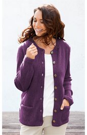 Lila Strickjacke mit langen Ärmeln, Rundhalsausschnitt, durchgehende Knopfleiste mit braunen Knöpfen, zwei aufgesetzte Taschen vorne, gerade geschnitten, getragen von lächelnder Frau mit dunklen Haaren, weiße Bluse und helle Hose darunter