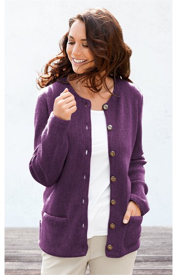 Lila Strickjacke mit langen Ärmeln, Rundhalsausschnitt, durchgehende Knopfleiste mit braunen Knöpfen, zwei aufgesetzte Taschen vorne, gerade geschnitten, getragen von lächelnder Frau mit dunklen Haaren, weiße Bluse und helle Hose darunter