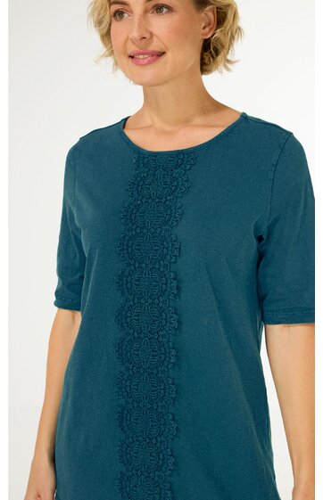 Dunkeltürkises Damenoberteil mit halblangen Ärmeln, Rundhalsausschnitt, florales Spitzenmuster mittig, gerade geschnitten, getragen von stehender Frau