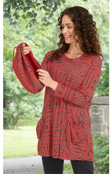 Rostrotes Langarmshirt mit schwarzem abstraktem Linienmuster, Rundhalsausschnitt, gerader Schnitt, getragen von lächelnder Frau, die passendes Tuch hält