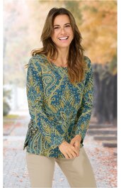 Langärmliges Oberteil in Blau und Grün mit Paisley-Muster, Rundhalsausschnitt, gerade geschnitten, getragen von stehender Frau mit nach vorne geneigtem Oberkörper, beige Hose