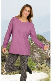 Langärmliges Shirt in altrosa, rundhals, gerade geschnitten, getragen von stehender Frau mit leicht gebücktem Oberkörper, kombiniert mit eng anliegenden, grau-schwarzen Leggings mit abstraktem Muster