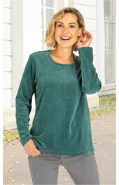 Langärmeliges Oberteil in dunkelgrün, ohne Muster, rundhalsausschnitt, gerade geschnitten, getragen von stehender Frau mit linker Hand in der Hosentasche