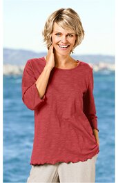 Rotes Langarmshirt ohne Muster, Rundhalsausschnitt, lockere Passform, locker sitzend, getragen von lächelnder Frau vor blauem Wasserhintergrund