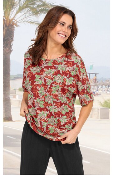 Rotes T-Shirt mit grünem und beigem floralem Muster, Rundhalsausschnitt, halblange Ärmel, lockere Passform, getragen von lächelnder stehender Frau, leicht geraffter Saum