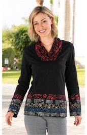 Langarmshirt schwarz mit buntem Blumenmuster in Rot, Blau und Beige entlang Saum und Ärmelenden, Rundhals mit weitem, gerüschtem Kragen, getragen von lächelnder stehender Frau