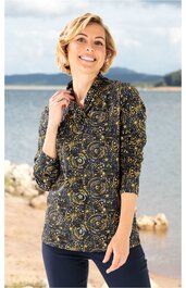 Langärmliges Blusenshirt in Dunkelblau mit gelbem und beigem Paisleymuster, Stehkragen mit Knopfverschluss, taillierter Schnitt, getragen von lächelnder stehender Frau vor Wasser und Felsen