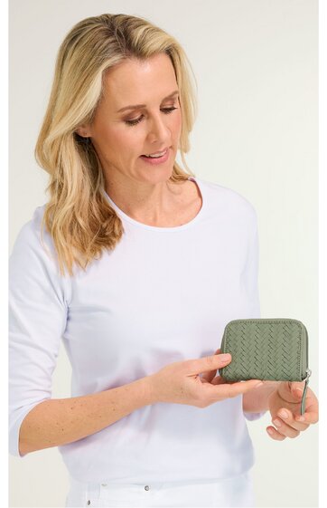 Kompakte Geldbörse in Olivgrün mit gewebter Struktur, rechteckige Form, Reißverschluss rundum, gehalten von Frau mit hellblondem, schulterlangem Haar, weiße Langarmbluse, stehende Pose, kleine Größe