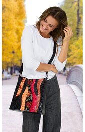 Weiße, langärmelige Bluse mit U-Ausschnitt, dunkelgraue Hose, bunte Umhängetasche mit abstraktem Muster in Rot-, Orange- und Schwarztönen, weibliche Person steht, hält Haare mit einer Hand, lächelt, herbstlicher Parkhintergrund mit gelben Bäumen