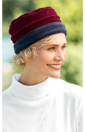 Damenmütze, bordeauxrot und dunkelblau, zweifarbig, eng anliegende Rollkanten, getragen von lächelnder Frau mit kurzem blondem Haar, Mütze bedeckt Kopf, rundum ohne sichtbare Öffnungen
