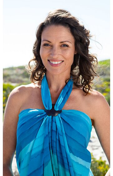 Blaues Strandkleid mit dunkleren Streifen, Halterkragen mit schwarzem Ring, ärmellos, getragen von lächelnder Frau mit lockigem Haar im Freien