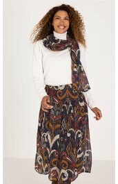 Weißer Rollkragenpullover, langärmlig, kombiniert mit langem, weichem Rock in mehrfarbigem Paisley-Muster, langer Schal mit gleichem Muster um den Hals gelegt, getragen von stehender Frau mit lockigen Haaren