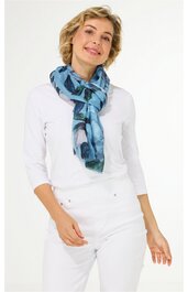 Hellblauer Schal mit dunklen und hellen blauen floralen Mustern, locker um den Hals gebunden, getragen von stehender Frau in weißem langärmligen Shirt und weißer Hose