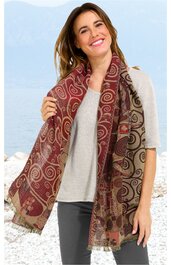 Schal in bordeauxrot mit braunen, beigen und goldfarbenen Spiralmustern, rechteckig, fransige Ränder, getragen von stehender lächelnder Frau mit grauem Kurzarmshirt und dunkler Hose