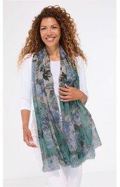 Grüne und graue längliche Schal mit Blumendruck, getragen von stehender Frau mit weißen Ärmeln und weißer Hose, locker fallend, transparent