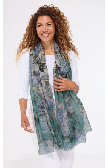Grüne und graue längliche Schal mit Blumendruck, getragen von stehender Frau mit weißen Ärmeln und weißer Hose, locker fallend, transparent