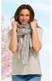 Hellbeiges Kurzarmshirt mit Rundhalsausschnitt, getragen von stehender Frau, dazu gemusterter Schal in Pastellfarben mit geometrischen Motiven, Schal locker um den Hals gelegt, blaue Jeans