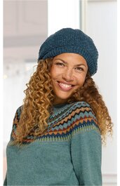 Damenpullover in grün mit mehrfarbigem Zickzackmuster am oberen Teil, Rundhalsausschnitt, lange Ärmel, getragen von lächelnder Frau mit lockigen Haaren, dunkelblauer Strickmütze