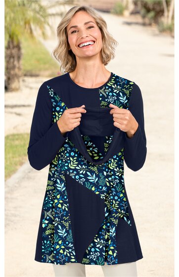 Langärmliges Damenoberteil in Dunkelblau mit Blumenmuster in Blau, Hellblau und Grün, Rundhalsausschnitt, V-förmige Musteraufteilung vorne, ausgestellte Form, getragen von lächelnder stehender Frau, Umstandsshirt mit seitlich eingearbeitetem Stillzug