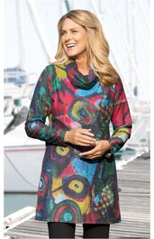 Langärmliges Kleid in dunklen Farben mit abstraktem, buntem Muster, Rollkragen, knielang, lockere Passform, getragen von lächelnder stehender Frau, Segelboote im Hintergrund