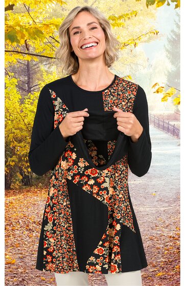 Schwarzes Langarmshirt mit mehrfarbigem Blumenmuster, Rundhalsausschnitt, asymmetrisches Design mit diagonal verlaufenden Blumenmusterelementen, getragen von lächelnder stehender Frau, lockere Passform
