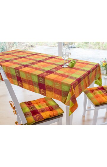 Tischdecke für Esszimmertisch, karierte Muster in Orange, Rot, Grün und Gelb, dekorative Apfel- und Blättermotive in den Karos, zwei weiße Holzstühle mit gepolsterten Sitzkissen in passenden Farben, aufgedeckter Tisch mit zwei Weingläsern und zwei gr