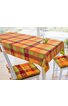 Tischdecke für Esszimmertisch, karierte Muster in Orange, Rot, Grün und Gelb, dekorative Apfel- und Blättermotive in den Karos, zwei weiße Holzstühle mit gepolsterten Sitzkissen in passenden Farben, aufgedeckter Tisch mit zwei Weingläsern und zwei gr