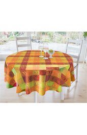 Runder Esstisch mit buntem Tischdeckenmuster in Rot, Orange, Gelb, Grün, quadratisch kariert mit Apfel- und Herzmotiven, zwei weißen Holzstühlen, im Hintergrund Gartenblick, auf dem Tisch zwei Weingläser mit Wasser und eine grüne Zierfrucht in Glasfu