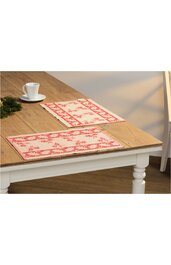 Rechteckige Tischsets in Cremeweiß mit rotem Blumenmuster, gesäumt, auf hellbraunem Holztisch mit weiß lackiertem Tischgestell, keine Personen sichtbar