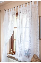 Weiße, halbtransparente Gardine mit zarten, grauen Zweigmuster, Schlaufenaufhängung, hängend vor braunem Holzfenster, teilweise zugezogen, Licht fällt durch Fenster, Dekoration mit Teddybär und Kerzen auf Fensterbank