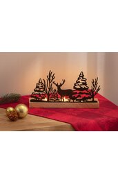 Schwarze Silhouetten aus Metall mit Wald- und Hirschmotiven auf braunem Holzsockel, warmes Hintergrundlicht, platziert auf rotem Tuch neben goldener Christbaumkugel und Tannenzweig mit Zapfen