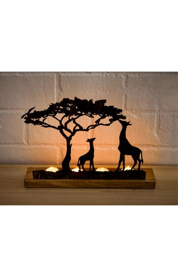 Dekorative Tischlampe mit Holzsockel, zwei Giraffen-Silhouetten, Akazienbaum-Silhouette, Warmlicht durch Kerzenlichteinsatz, Hintergrund mit weißem Backsteinmauer, natürliche Holzfarbe, rechteckige Grundform