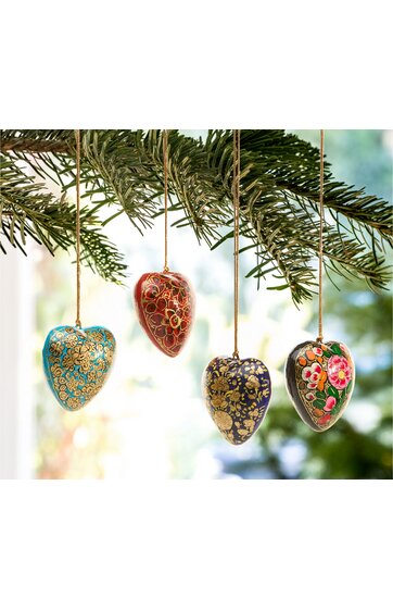 Herzförmige Christbaumkugeln in Blau, Rot, Dunkelblau und Grau mit goldenem Muster und rosa Blüten, hängend an grünen Tannenzweigen, glänzend, mit Aufhängefaden