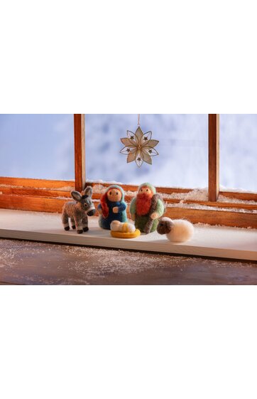 Weihnachtskrippe mit Filzfiguren in Blau, Grün und Beige, bestehend aus Maria, Josef, Esel und Schaf, Plastik-Krippe mit gelbem Kreis und weißen Kugeln, davor hängender weiß-beiger Stern, auf weißem Fensterbrett vor Holzfenster